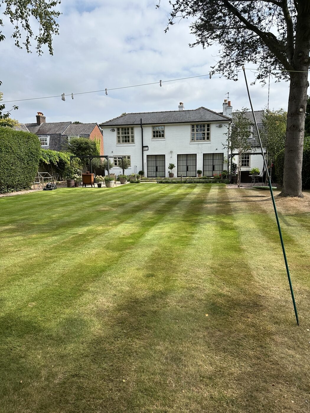 Maintained lawn with neat mowing stripes beside a family home